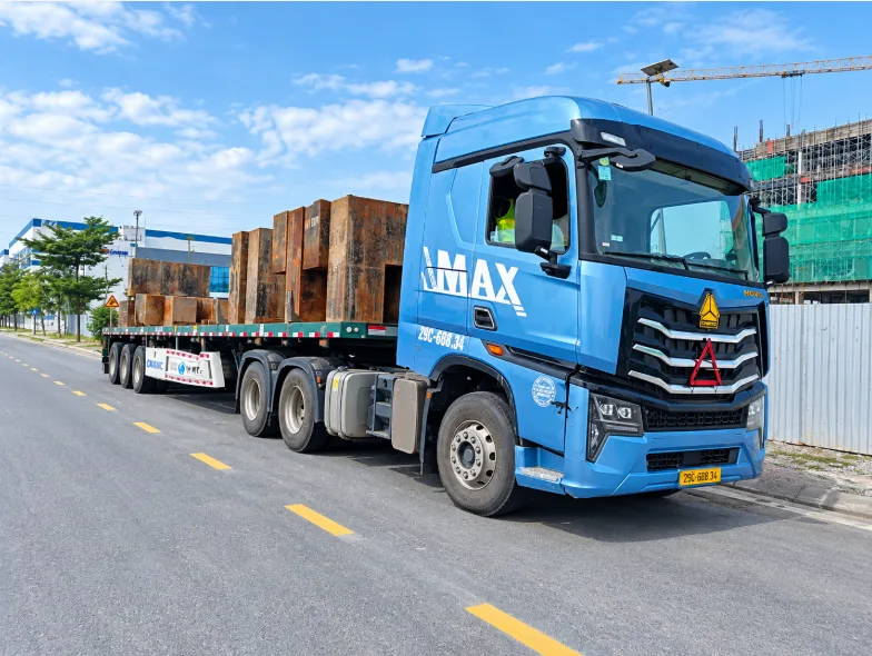 Xe đầu kéo xanh chở tải sắt trên sơ mi rơ moóc tại công trường